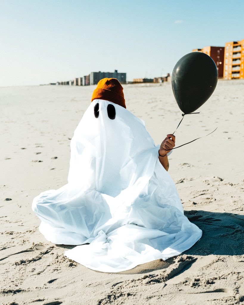 A ghost holding black balloon waiting for birthday cake